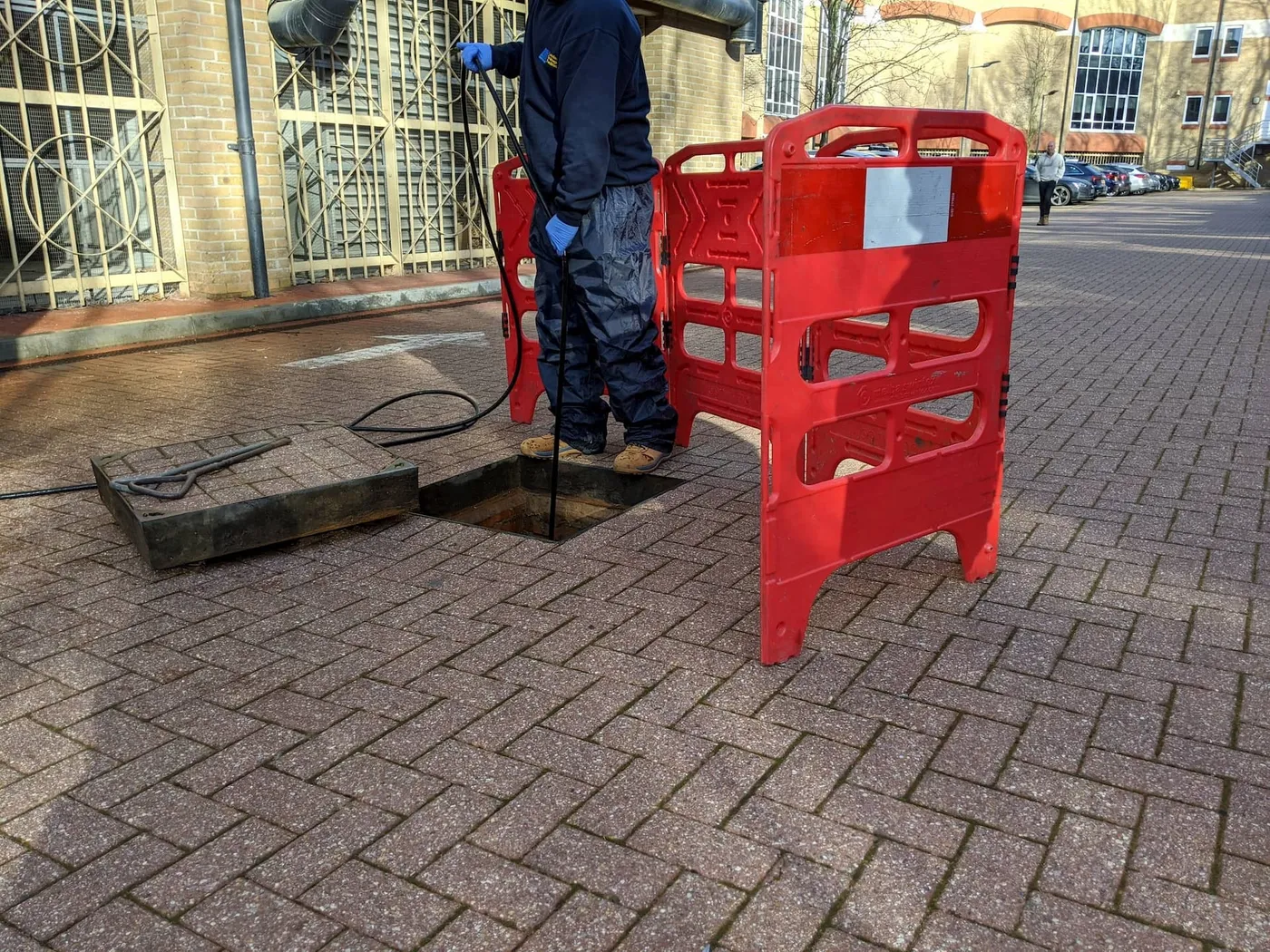 Drainage engineer working at an open manhole on a London street